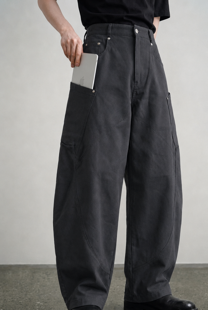 Grey carpenter pants angled view showing curved panel seams and utility pocket, on model